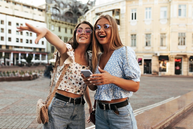 mujeres-alegres-atractivas-elegantes-atuendos-verano-miran-distancia-sorpresa-emocionadas-chicas-rubias-morenas-coloridas-gafas-sol-posan-al-aire-libre-sonrien_197531-27726